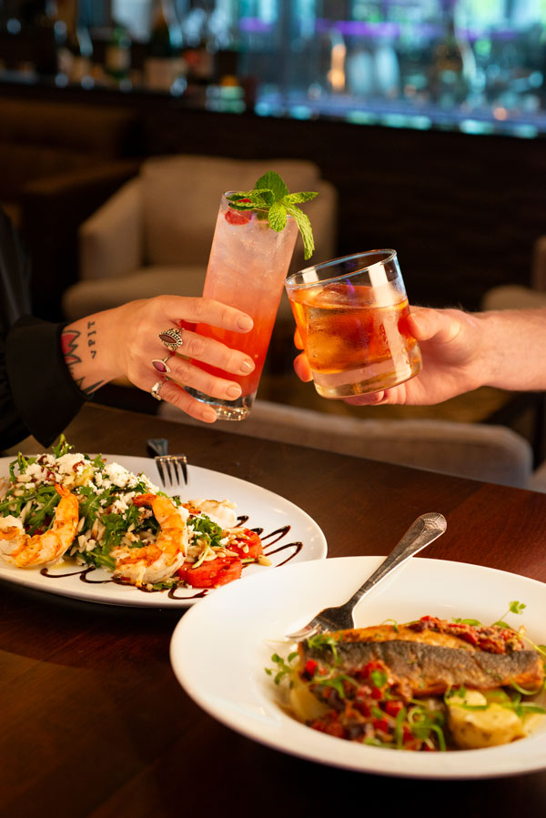 Cheers-in-shadows-lounge-Shadows-Batch2-12 Couple cheers cocktails with their entrees in the lounge of Shadows on the Hudson