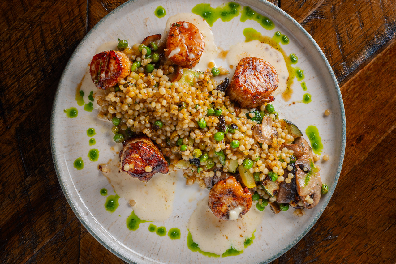 Shadows-on-the-Hudson-Summer2026-specials-entrees-3 Seared scallops over pearl couscous with green sauce.